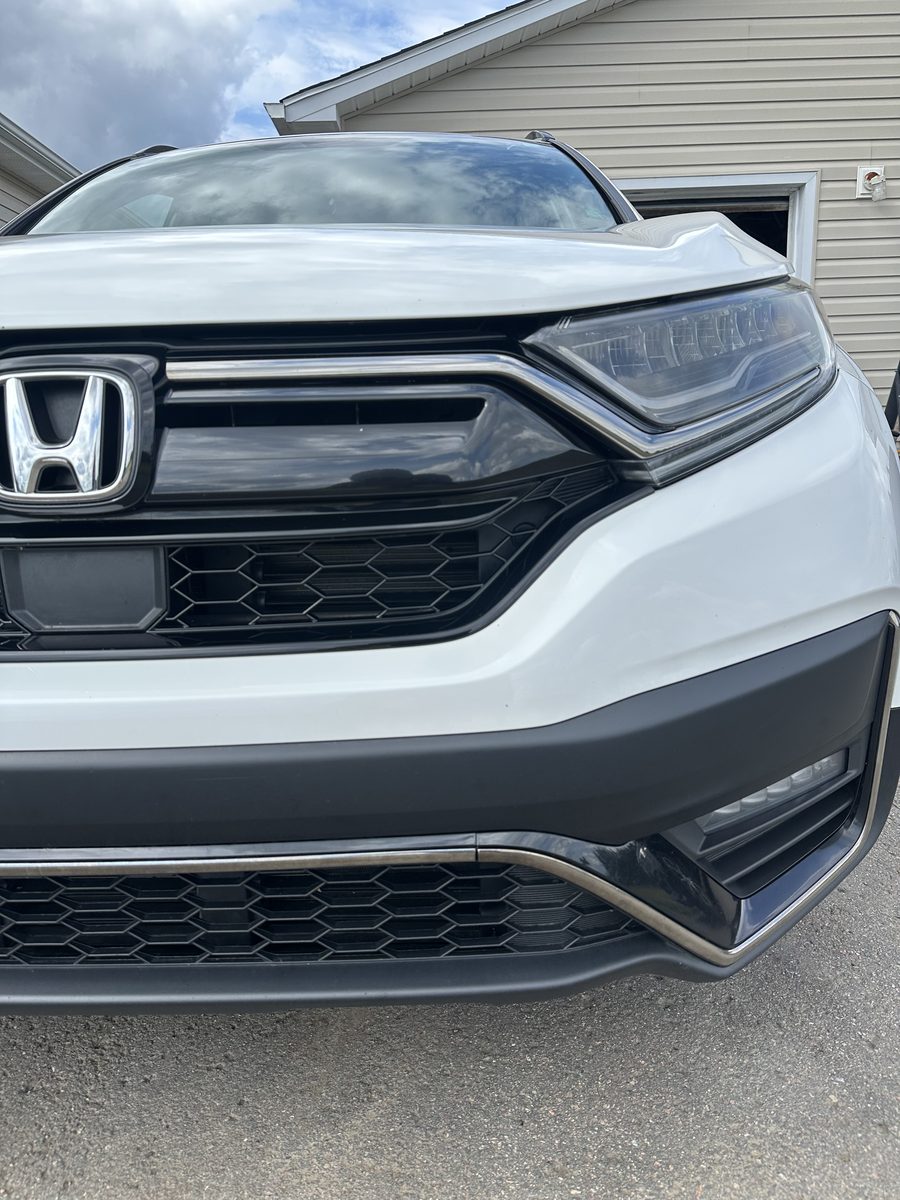 Clean, glossy white SUV grille and hood after an exterior detail