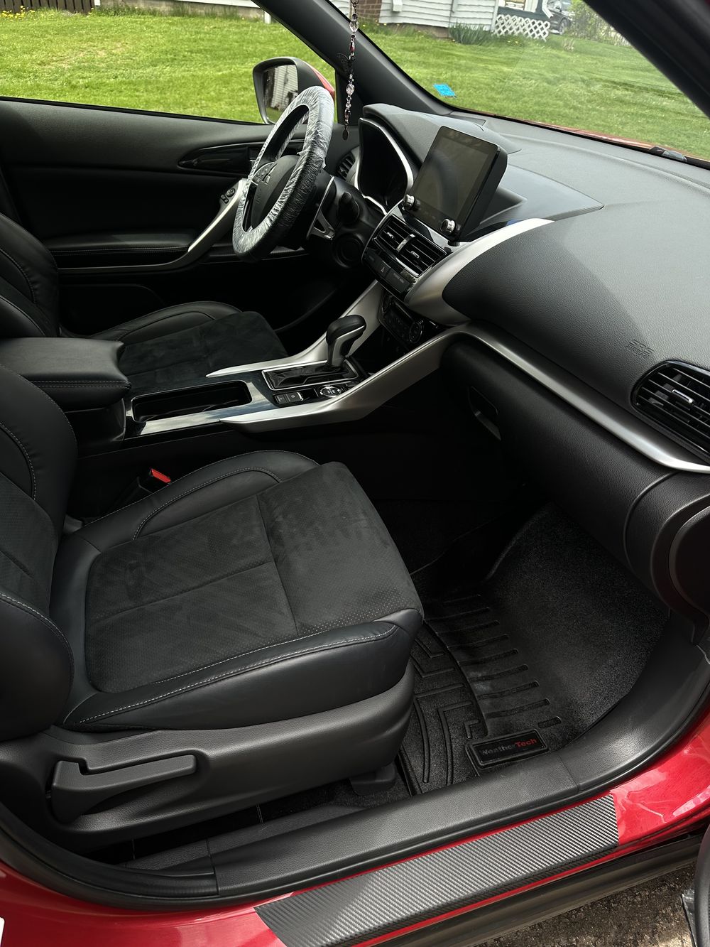 Clean, freshly detailed black leather car interior with protective wrap still on the steering wheel